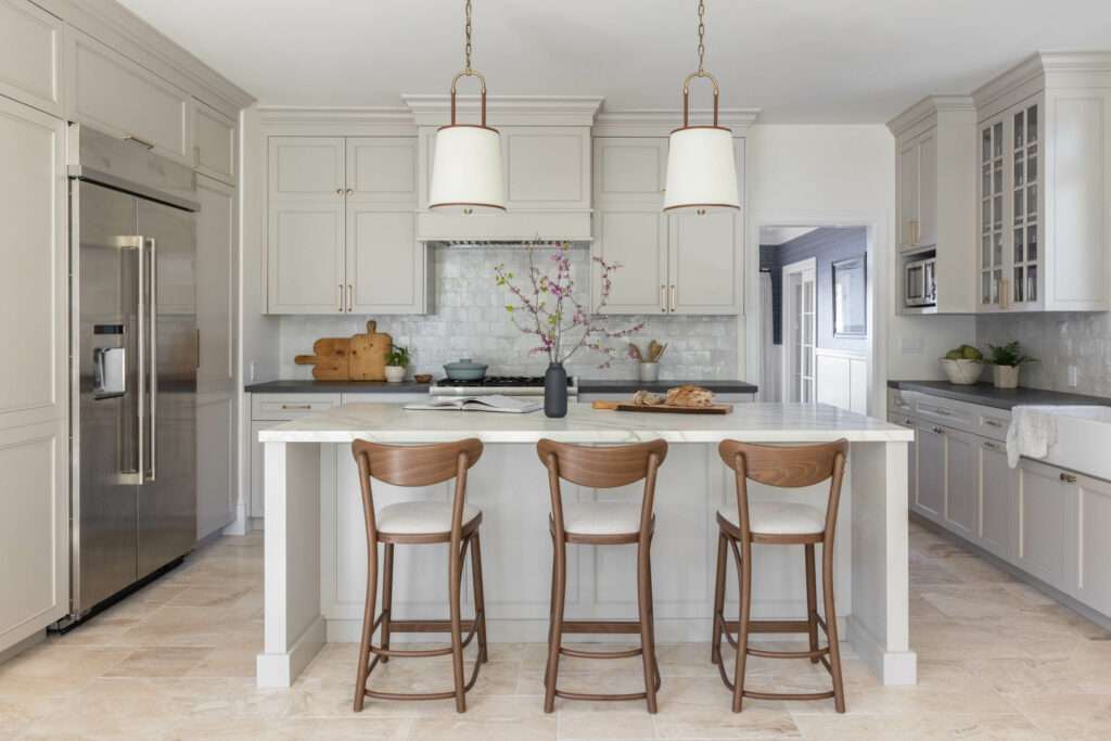 Marin County interior designer, Revelry Interior Design, kitchen renovation showing an island with walnut barstools calacatta marble island and white pendants with brass hardware on the taupe beige neutral cabinetry